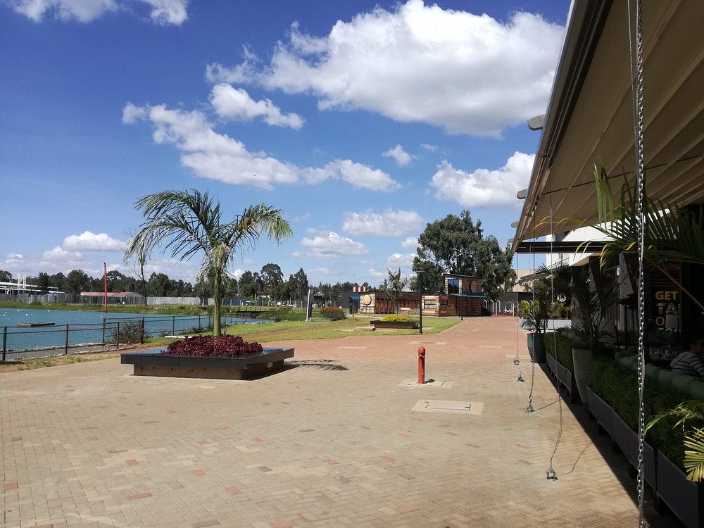 The lakeside promenade at The Waterfront Karen — brick paving, palms and open water